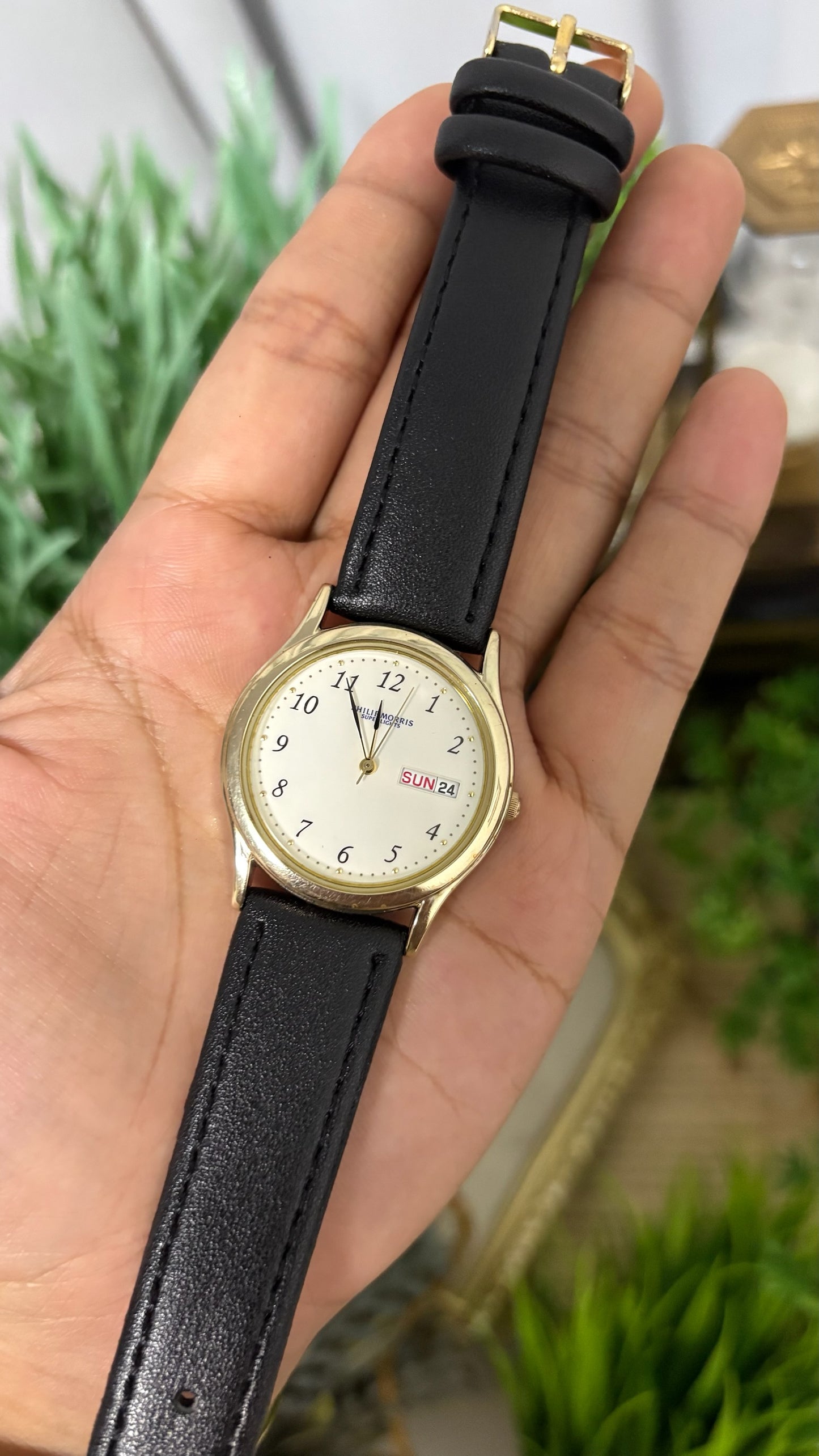 Vintage Philip Morris Super Lights Mens Round Watch with White Dial Full Arabic Numerals Day Date Window Polished Gold Tone Case and Smooth Black Leather Strap Quartz